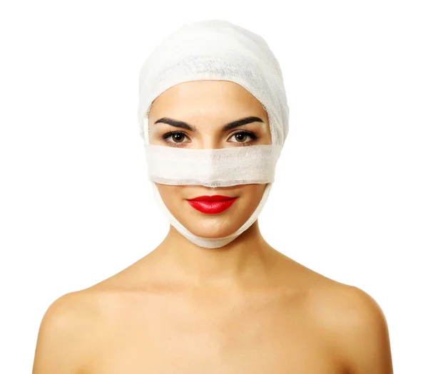 Mulher bonita nova com uma bandagem de gaze na cabeça e no nariz, isolada em branco — Fotografia de Stock