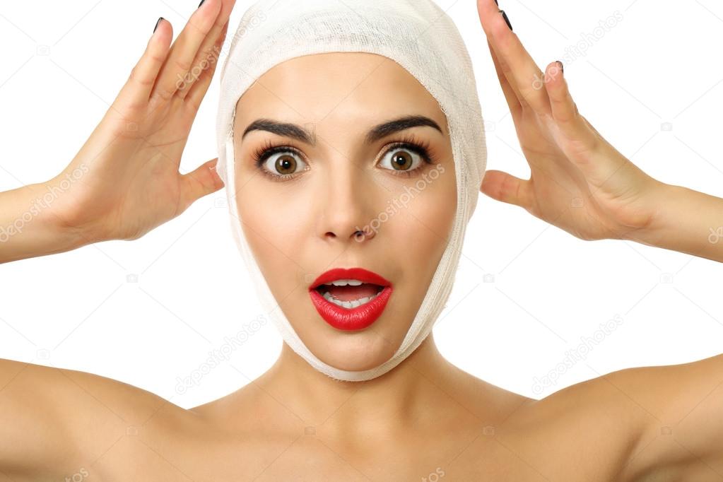 Young emotional woman with a gauze bandage on her head, isolated on white, close-up