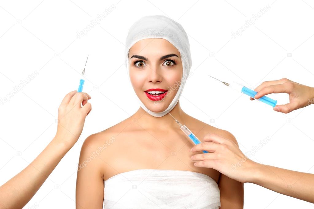 Young beautiful woman with a gauze bandage on her head and chest, having injections, isolated on white