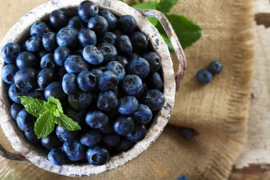 Lezzetli olgun yaban mersini masada kova yeşil yaprakları ile yakın çekim