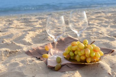 Beyaz şarap ve üzüm kum plajındaki romantik kompozisyon