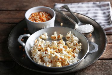 Ahşap masa üzerinde Mısır Kupası ile metal bir kase tuzlu popcorn