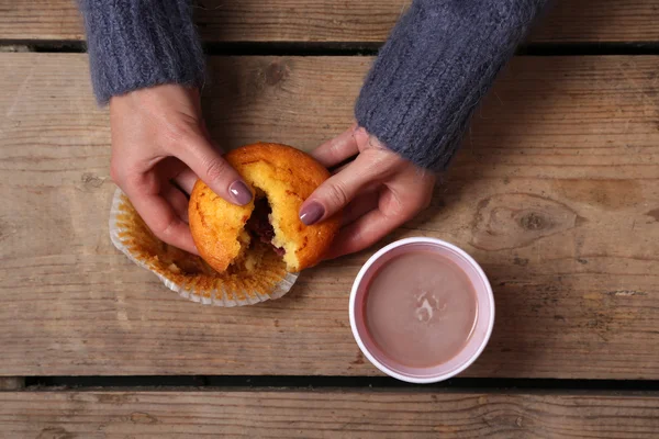 Female hands holding cup of coffee and cookies on wooden table close up — Stock Photo, Image