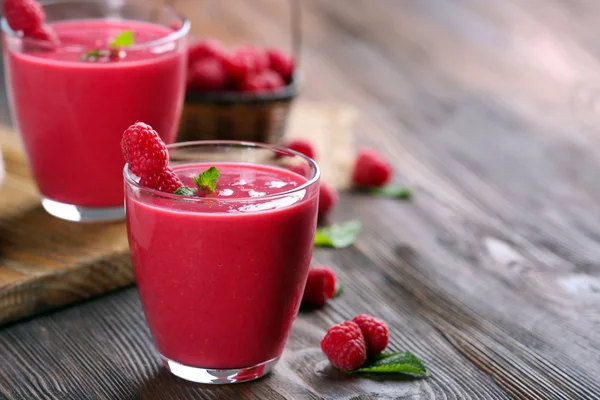 Glasses of raspberry milk shake with berries on wooden table close up — Stock Photo, Image