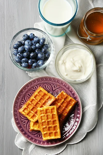 Sweet homemade waffles on plate, on color wooden background — Stock Photo, Image