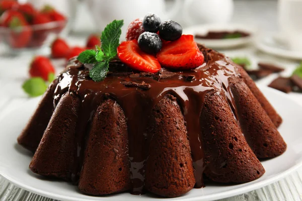 Delicioso pastel de chocolate con bayas en plato en la mesa, primer plano —  Fotos de Stock