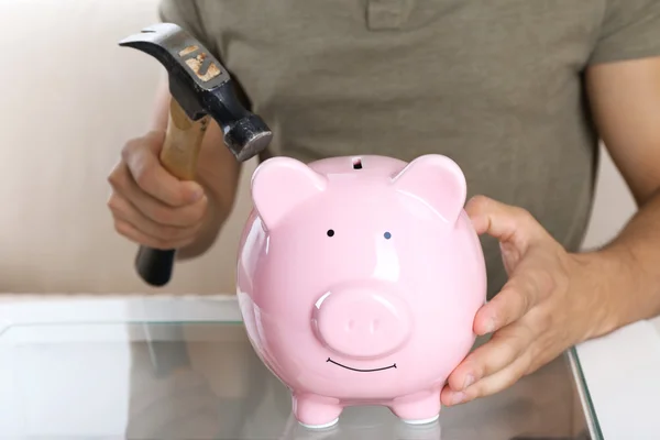Man met de hamer gaan om te breken piggy bank — Stockfoto
