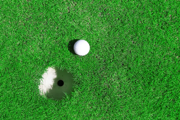 Pelota de golf en el labio de la taza en el campo de golf verde — Foto de Stock