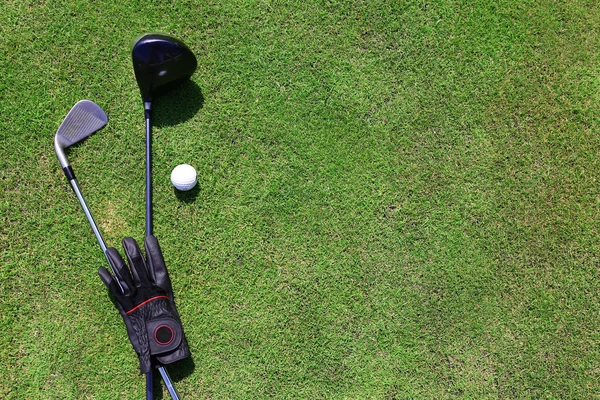 Golf klubok a labdát, és a zöld fű, fekete kesztyű közelről — Stock Fotó