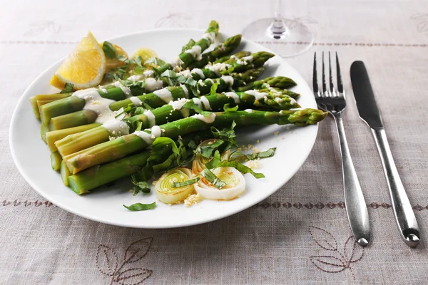 Appetitanregender Spargel in Sauerrahmsoße mit Zwiebeln, Käse und Zitrone auf dem Tisch, Nahaufnahme — Stockfoto