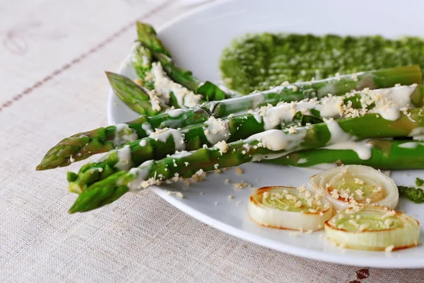 Delicious asparagus dish with onions and green sauce on the table — Stock Photo, Image