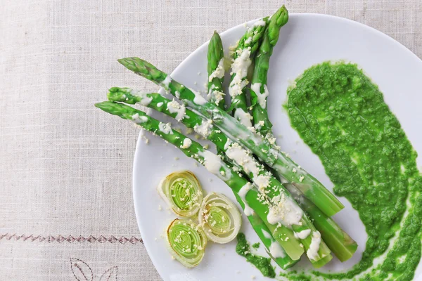 Delicious asparagus dish with onions and green sauce on the table — Stock Photo, Image