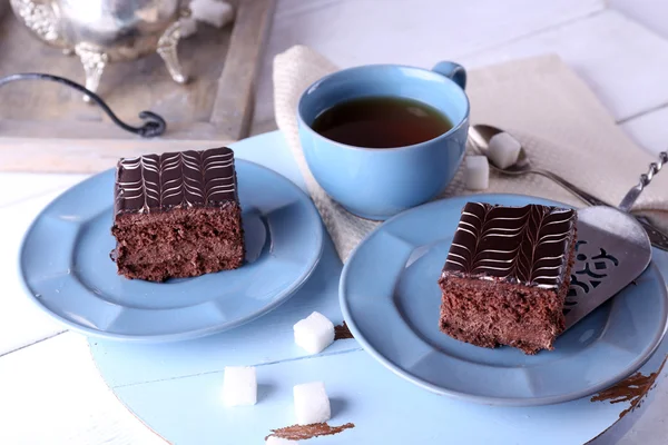 Сервированный стол с чашкой чая и шоколадными тортами на синих тарелках крупным планом — стоковое фото