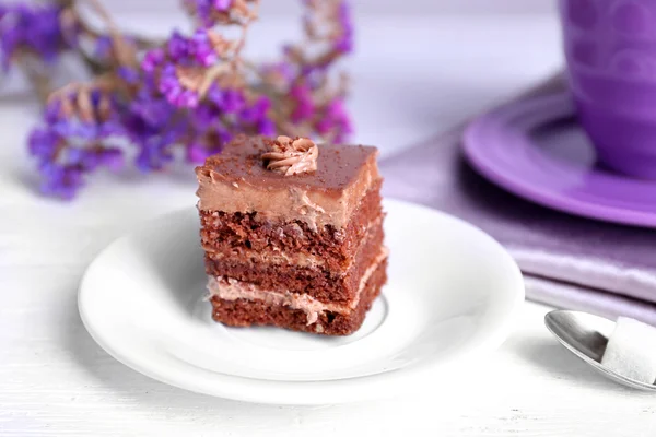 Tavolo servito con torta al cioccolato e una tazza di tè su sfondo bianco in legno — Foto Stock