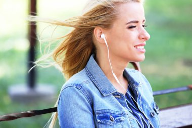 Bankta oturan ve müzik parkta genç kadın