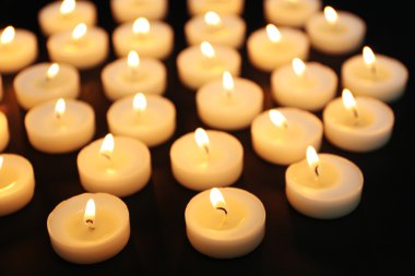 Siyah arka plan üzerine üst üste mum yanıyor