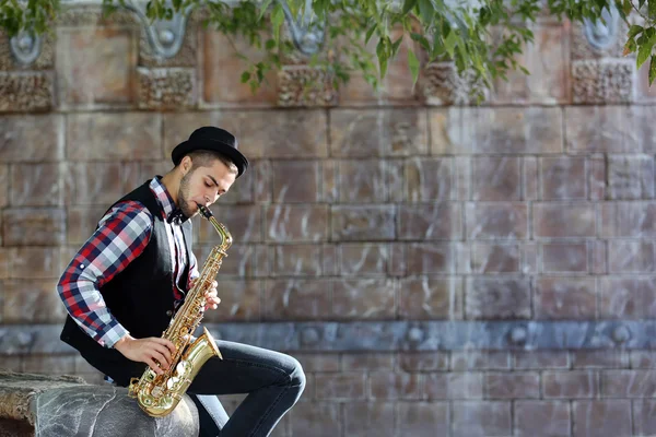 Handsome young man plays sax