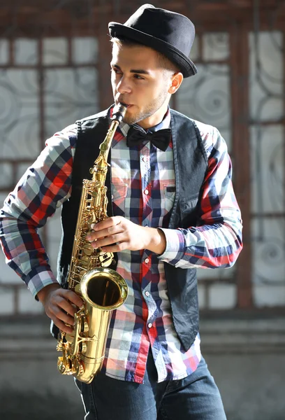 Young handsome man plays saxophone — Stock Photo, Image