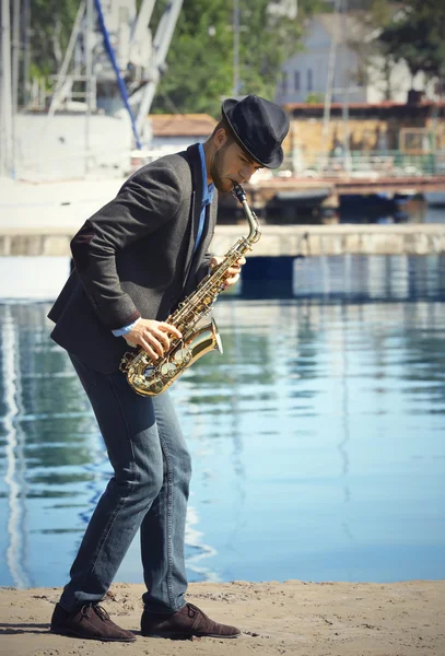 Joven hombre guapo toca el saxofón — Foto de Stock