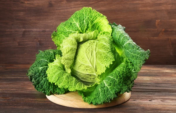 Savoy cabbage on cutting board on wooden background — Stock Photo, Image