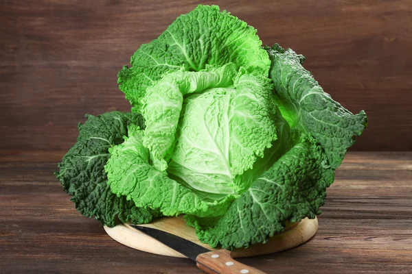 Savoy cabbage on cutting board on wooden background — Stock Photo, Image