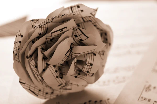 Paper-made rose on musical notes pages — Stock Photo, Image