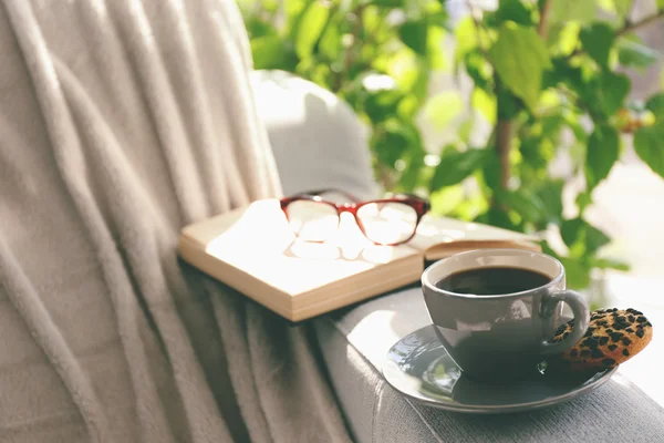 Cup of coffee with book on sofa in room — Stock Photo, Image