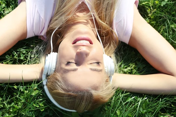 Jeune femme dans les écouteurs sur l'herbe — Photo