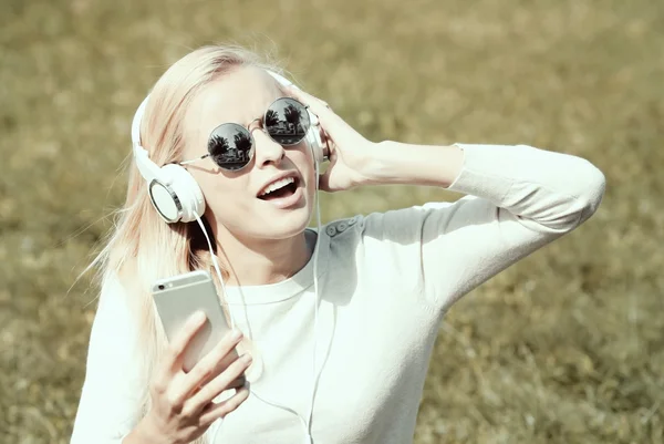 Красивая женщина слушает музыку с наушниками на открытом воздухе — стоковое фото