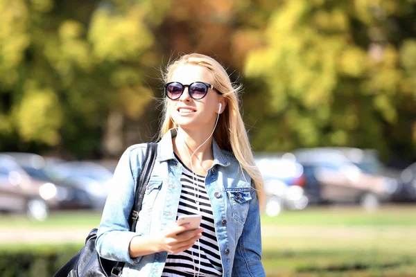 Junge Frau hört Musik und geht die Straße entlang — Stockfoto