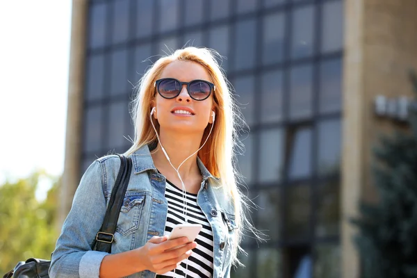 Junge Frau hört Musik und geht die Straße entlang — Stockfoto