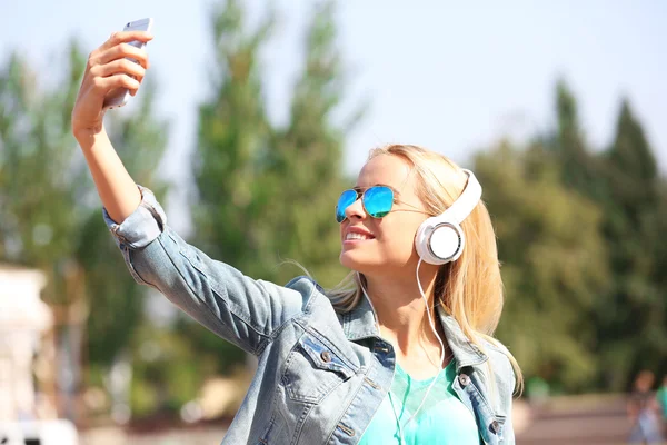 Mladá žena, poslechu hudby a a odběr selfie mimo — Stock fotografie