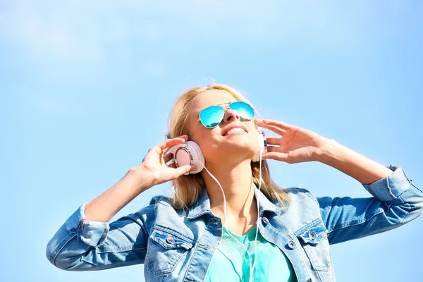 Mujer joven escuchando música en el fondo del cielo —  Fotos de Stock