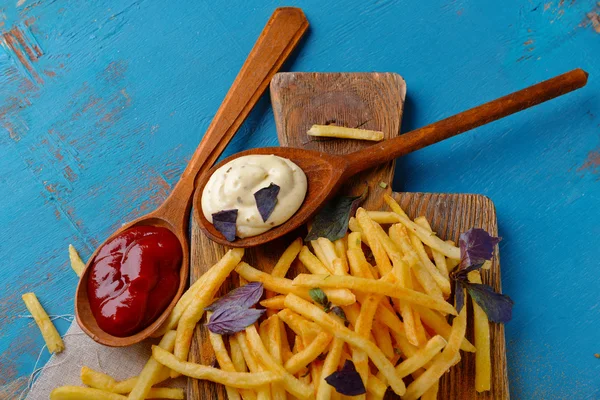 Frans gebakken aardappelen met saus op snijplank — Stockfoto