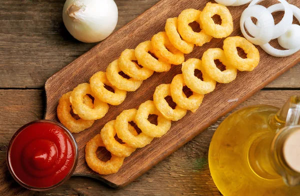 Pommes-Ringe mit Sauce und Zwiebeln auf Schneidebrett — Stockfoto