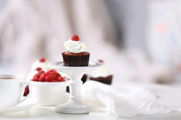 Bellissimi cupcake al cioccolato con crema e lampone sul tavolo — Foto Stock
