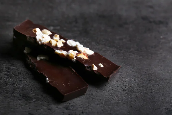 Černé kousky čokolády a ořechy na tmavě šedém pozadí — Stock fotografie