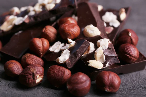 Black chocolate pieces and nuts on dark gray background — Stock Photo, Image