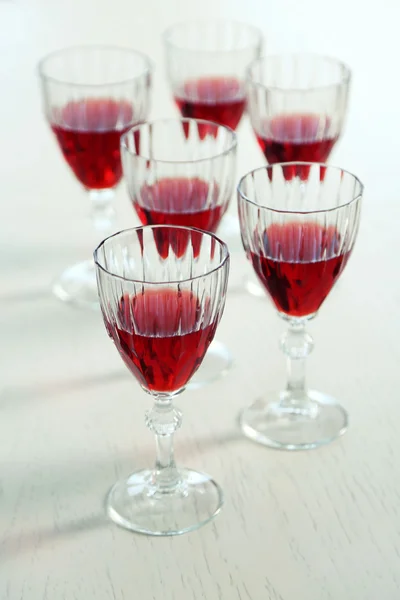 Glasses of red wine on table on bright background — Stock Photo, Image