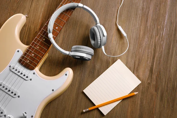 Guitarra elétrica com fones de ouvido em fundo de madeira — Fotografia de Stock