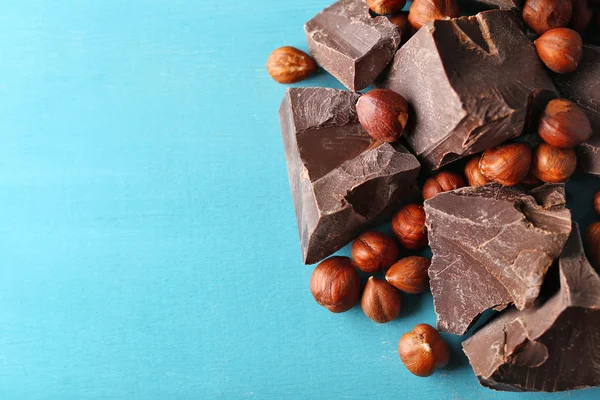 Svart choklad bitar med nötter på färg trä bakgrund — Stockfoto