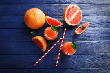 Greyfurt suyu şişeleri ve koyu mavi ahşap zemin üzerine taze meyve