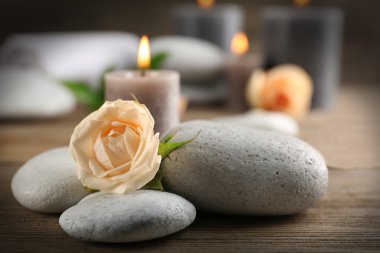 Ahşap arka plan üzerinde gri mum gül ve çakıl yanıyor - kavramı relax