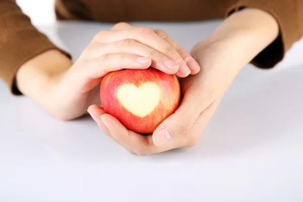Red apple with heart in hands