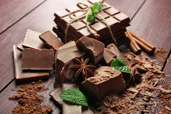 Různé kousky čokolády, kávy a kakaový prášek na dřevěné pozadí — Stock fotografie