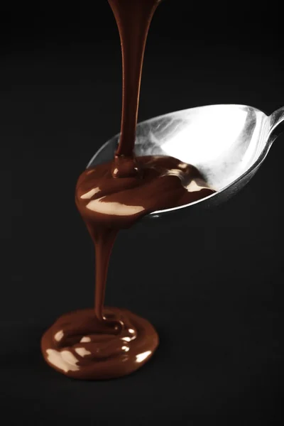 Chocolate poured on a spoon on dark background — Stock Photo, Image