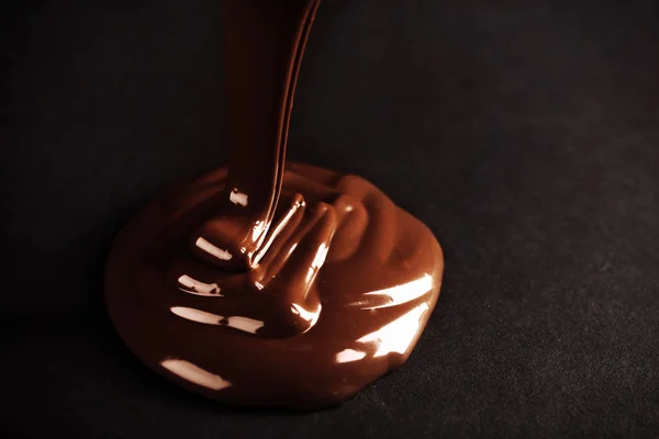 Chocolate poured on dark surface — Stock Photo, Image