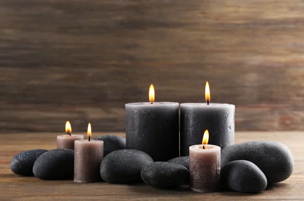 Κερί αναμμένο κερί γκρι με βότσαλα γύρω σε ξύλινα φόντο — Φωτογραφία Αρχείου