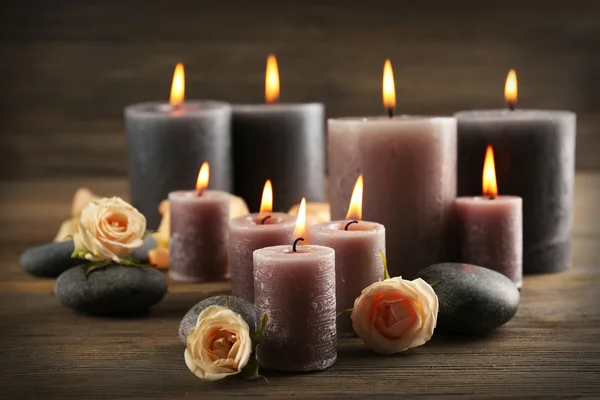 Velas grises de cera clara con rosas sobre fondo de madera — Foto de Stock