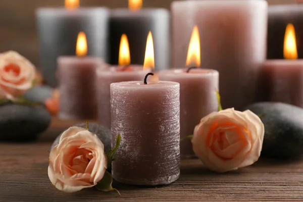 Candele grigio cera chiaro con rose su sfondo di legno — Foto Stock